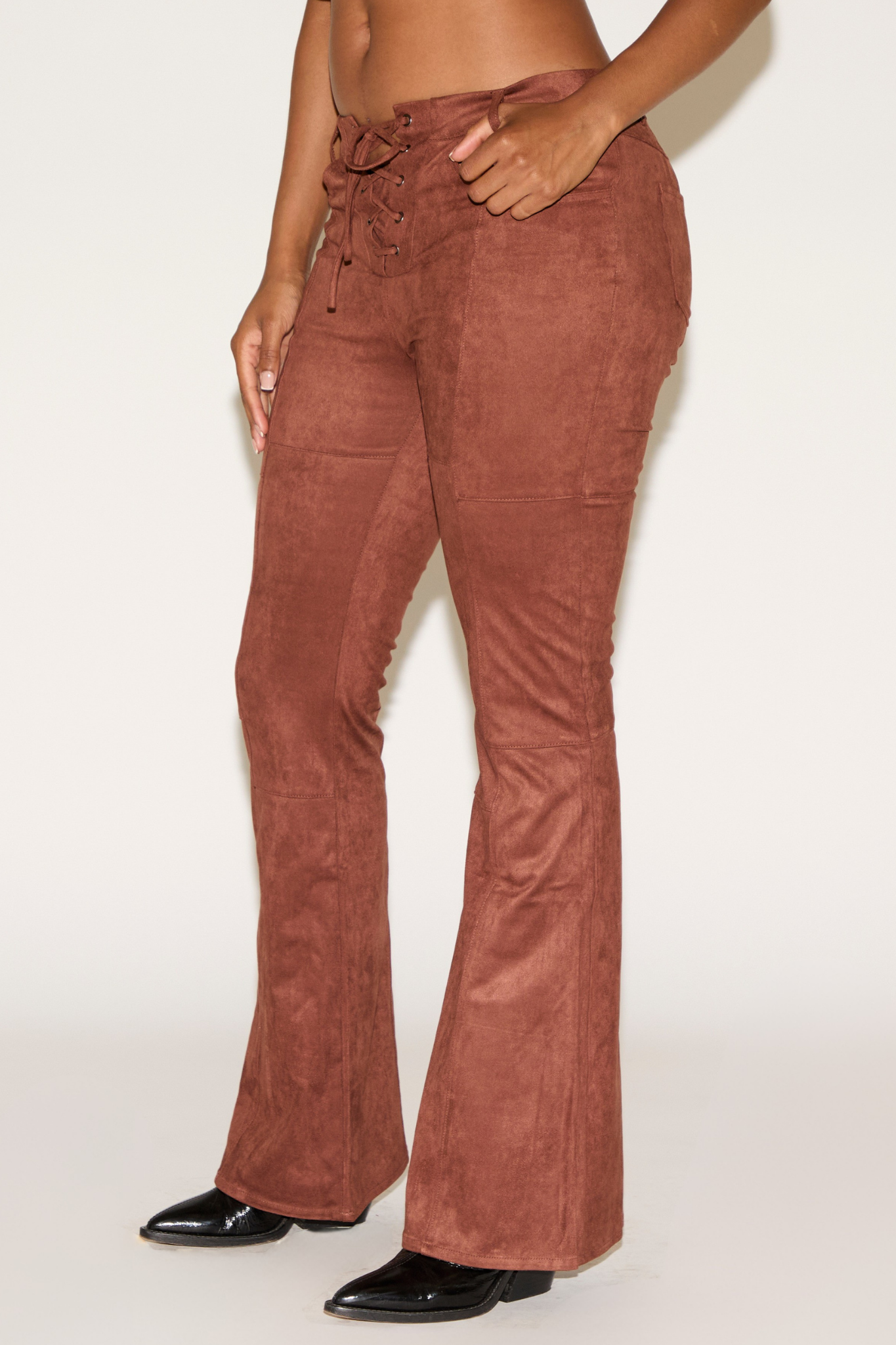 Brown corduroy pants worn by a person on a white background