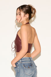 Woman wearing a brown leather top and blue jeans against a white background