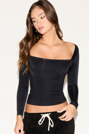 Woman wearing a black off-shoulder top against a white background
