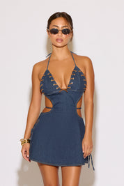 Woman wearing a blue denim dress with cut-out details on a white background