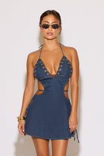 Woman wearing a blue denim dress with cut-out details on a white background