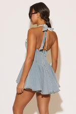 Woman wearing a denim dress with thin straps on a plain background