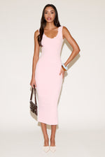 Woman wearing a pink sleeveless dress against a white background