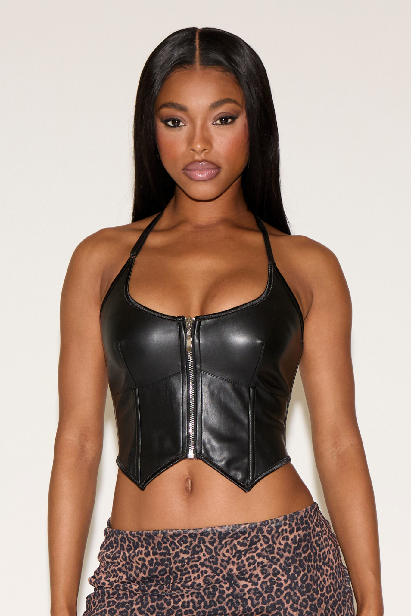 Woman wearing a black leather crop top with a white background