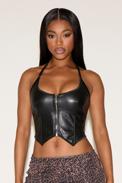 Woman wearing a black leather crop top with a white background