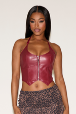 Woman wearing a red leather halter top with a white background