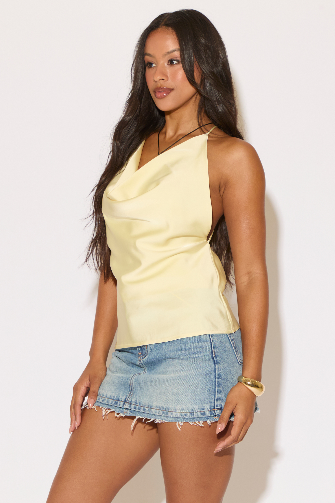 Woman wearing a yellow top and denim shorts against a white background