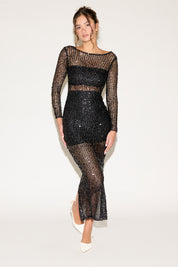 Woman wearing a black sheer dress with long sleeves on a white background