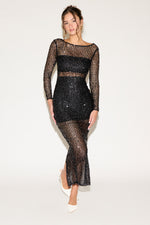 Woman wearing a black sheer dress with long sleeves on a white background