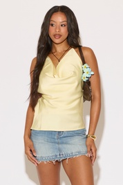 Woman wearing a yellow top and denim skirt with a white background