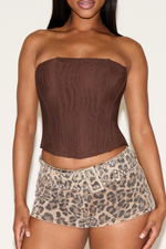 Woman wearing a brown strapless top and leopard print shorts against a white background