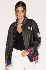 Woman wearing a black leather jacket with colorful trim on a white background