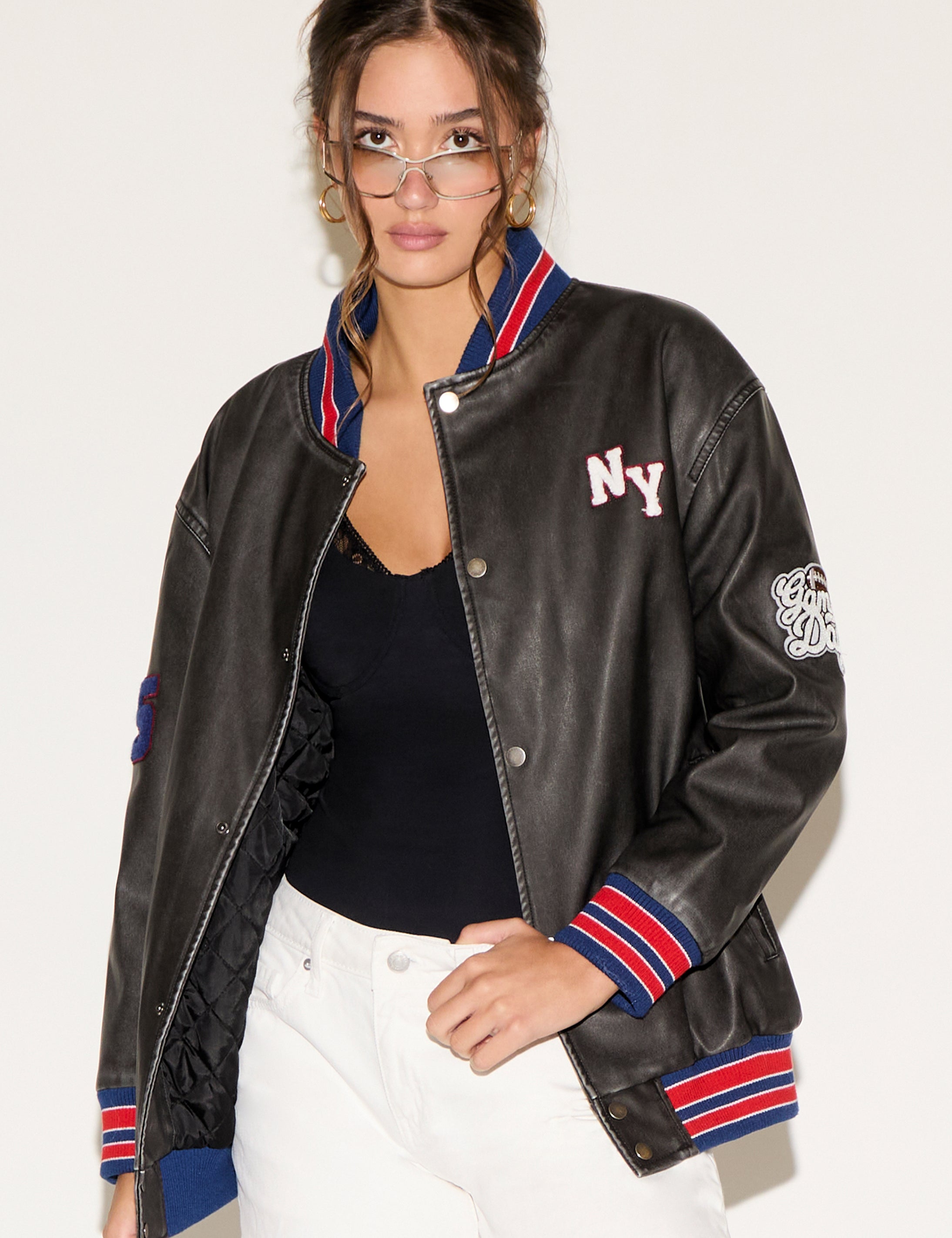 Woman wearing a black leather jacket with colorful trim on a white background