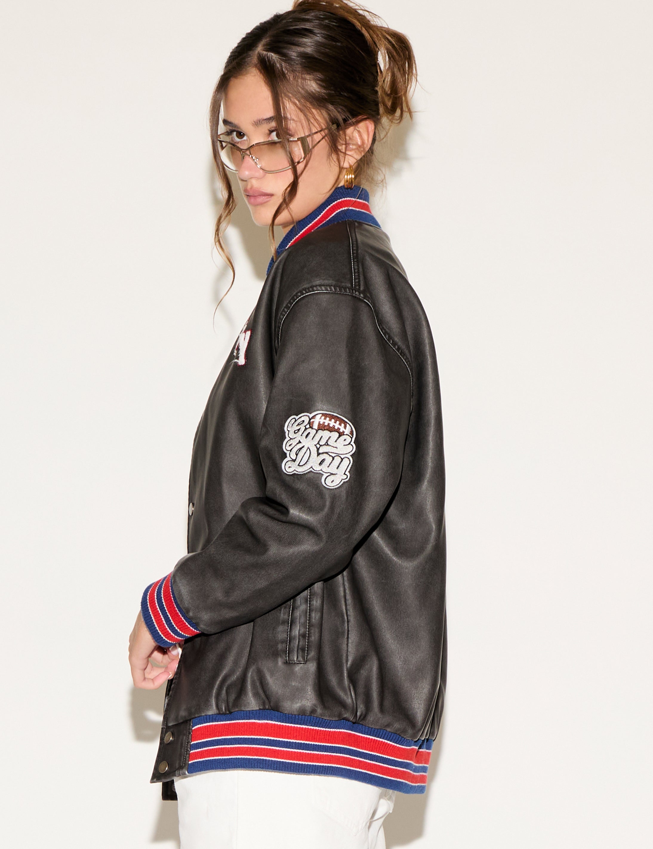 Person wearing a black varsity jacket with colorful accents on a white background