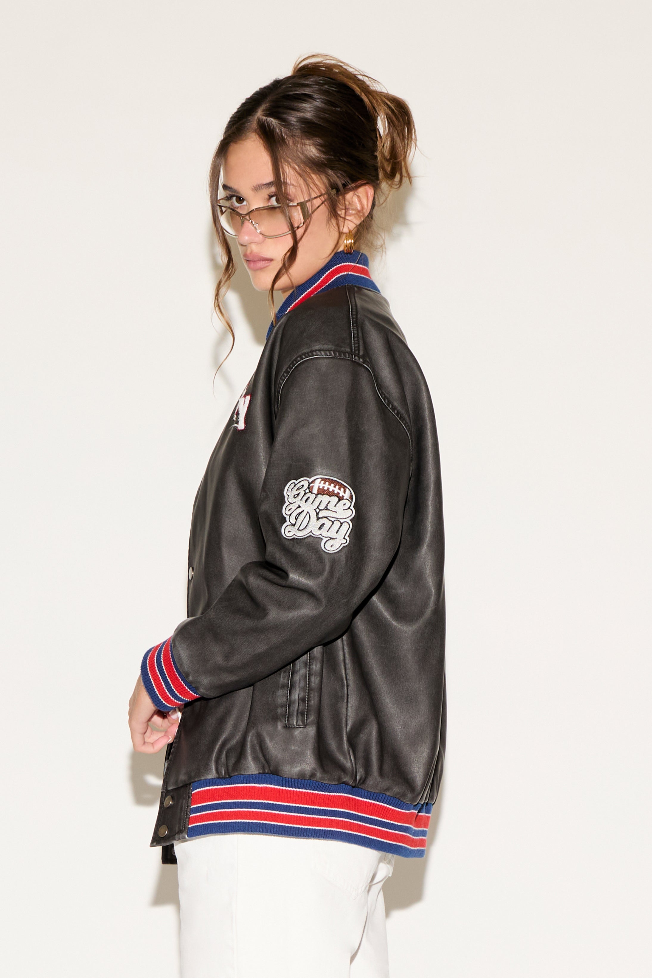 Person wearing a black varsity jacket with colorful accents on a white background