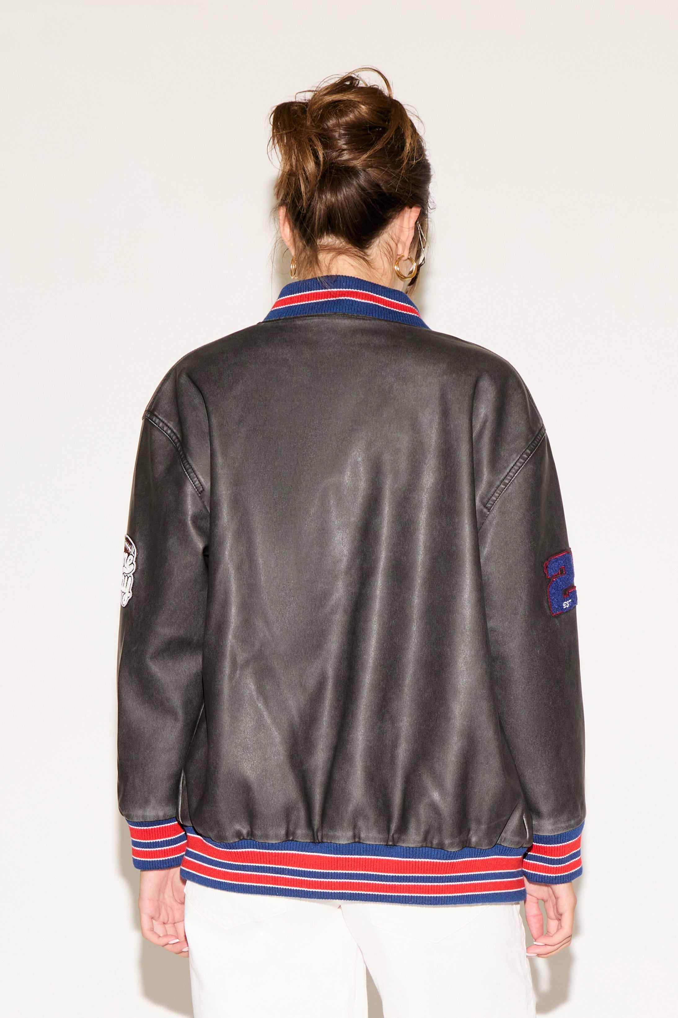 Person wearing a gray leather jacket with colorful accents on a white background