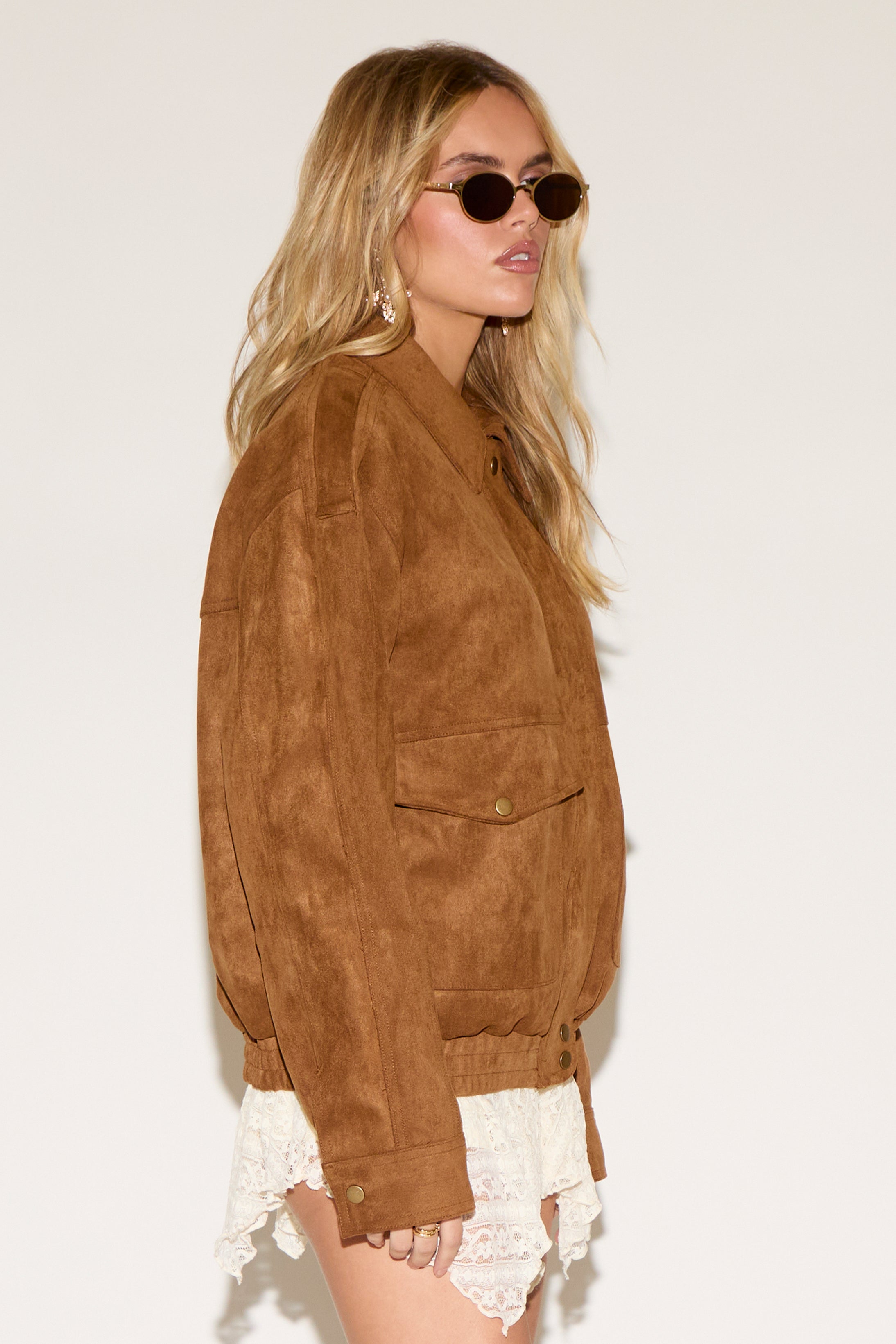 A women wearing a brown jacket in a white background.