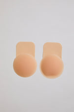 Two beige silicone bra cutlets on a light gray background