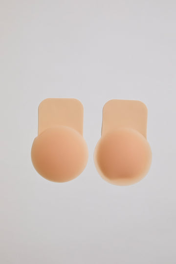 Two beige silicone bra cutlets on a light gray background
