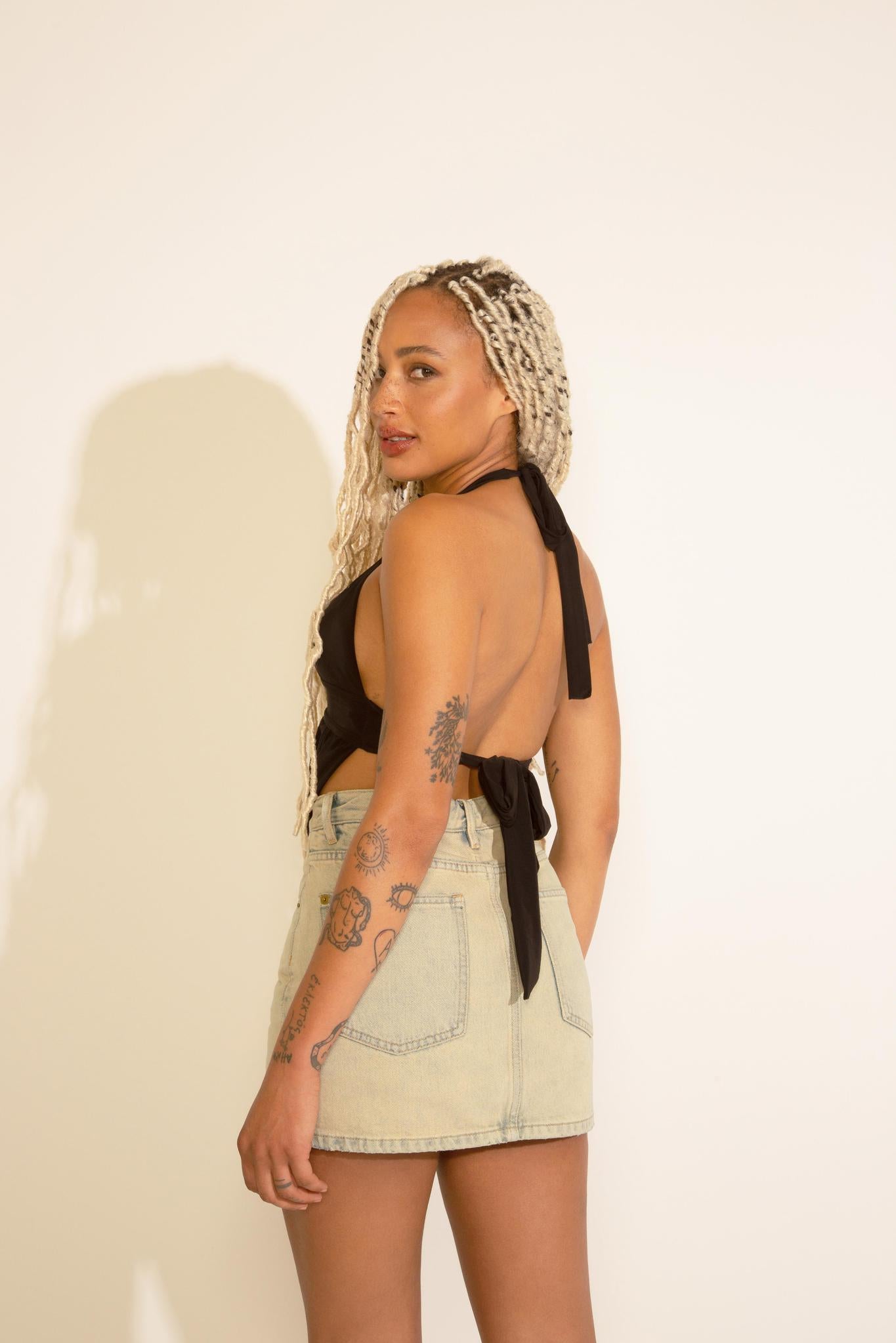 A person wearing a black top and beige acid wash denim A-line mini skort.