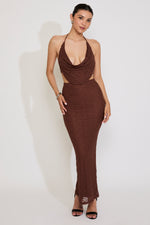 Woman wearing a brown halter neck dress against a white background