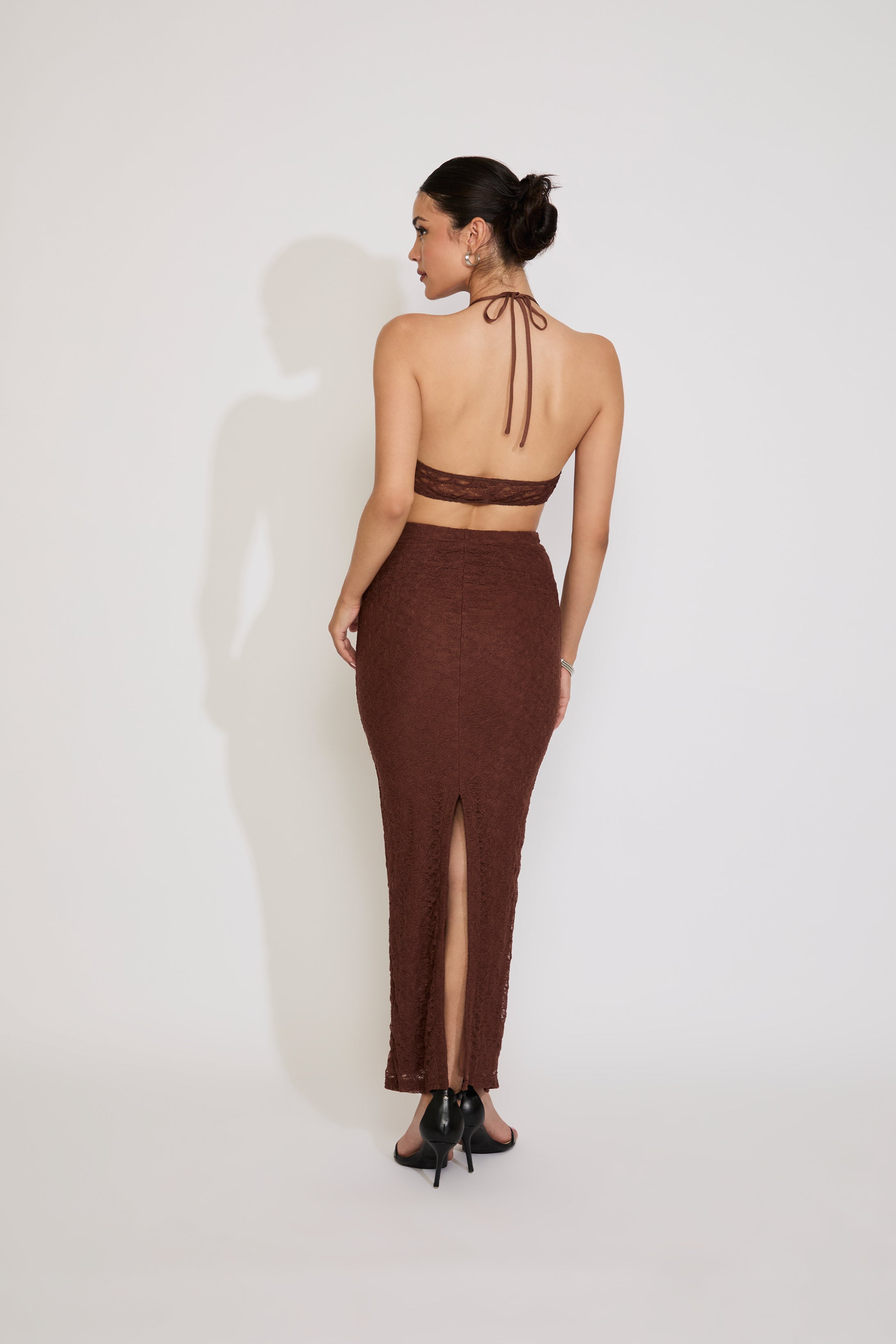 Woman wearing a brown dress with a sheer overlay on a white background