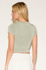 Model wearing a green cropped short-sleeve t-shirt with white jogger pants