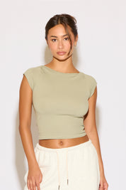 Woman wearing a light green crop top and white pants against a plain background