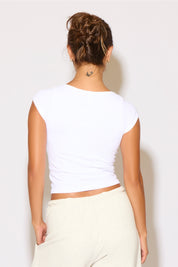 Person wearing a white crop top and light-colored pants against a plain background