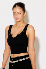 Woman wearing a black crop top with embellishments against a white background