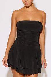 Black strapless dress worn by a model against a white background