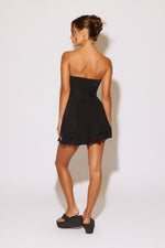 Woman wearing a black strapless dress against a white background