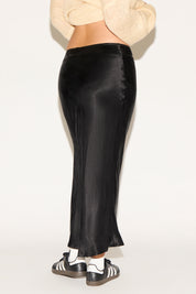 Black satin skirt worn by a person on a white background