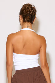 Person wearing a white strapless top and brown pants against a plain background