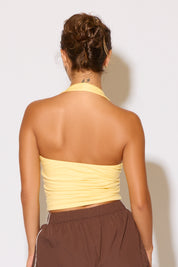 Person wearing a yellow strapless top and brown pants against a white background