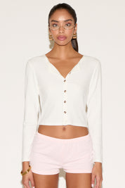 Woman wearing a white long-sleeve top and pink shorts on a white background