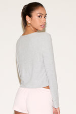 Woman wearing a light gray sweater and pink shorts on a white background