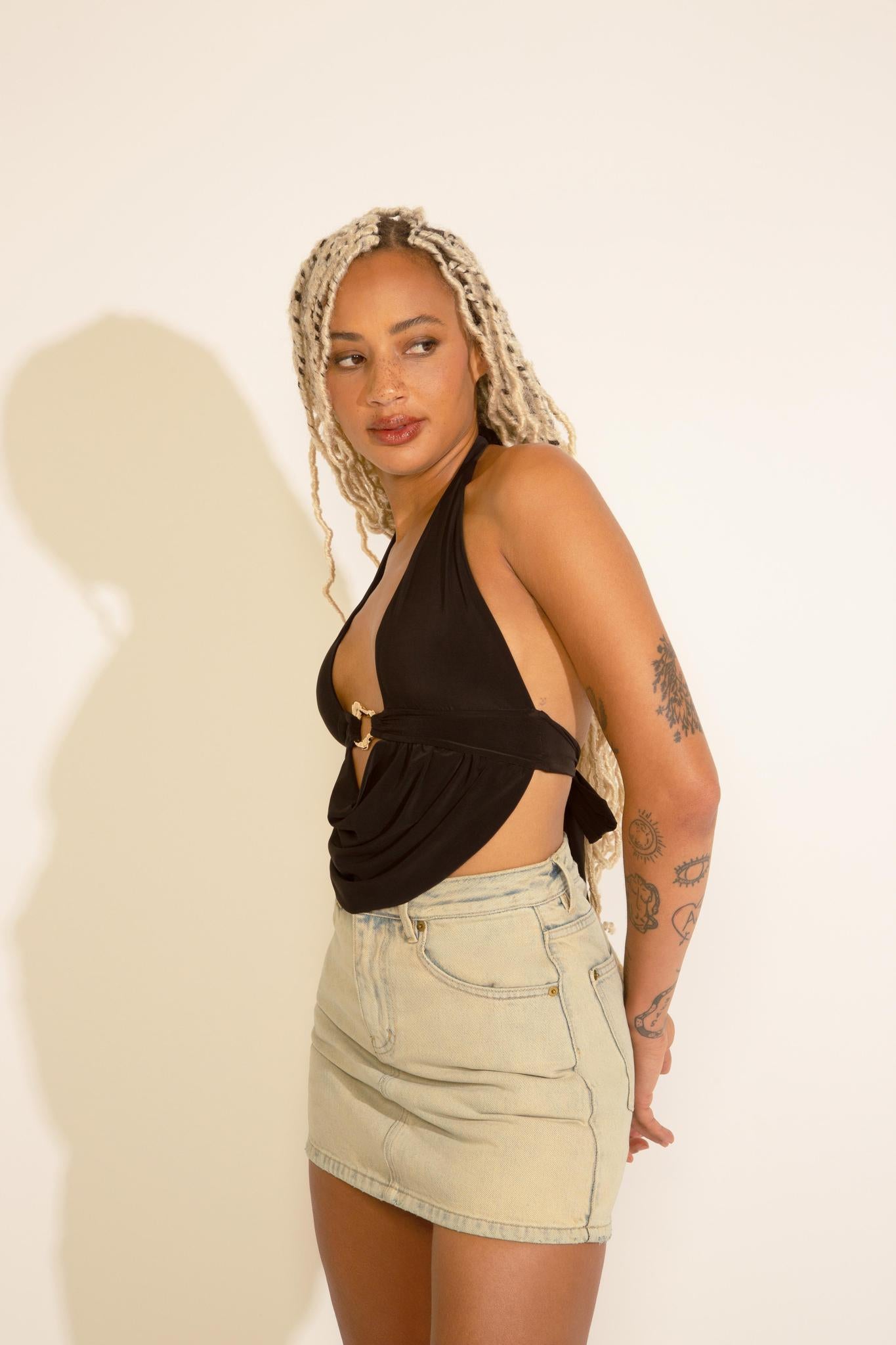 A person wearing a black top and beige acid wash denim A-line mini skort.