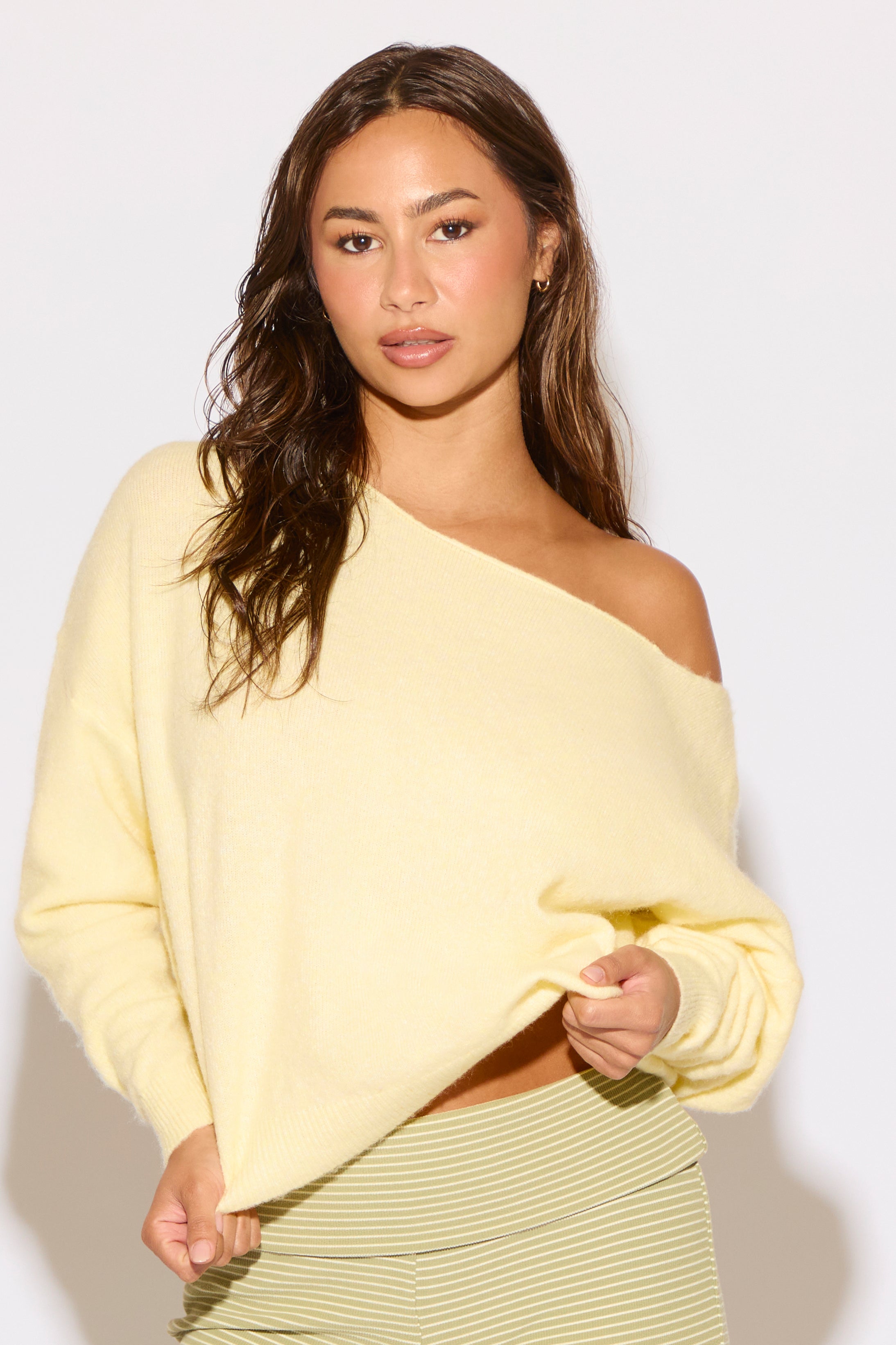 Woman wearing a yellow off-shoulder top against a white background