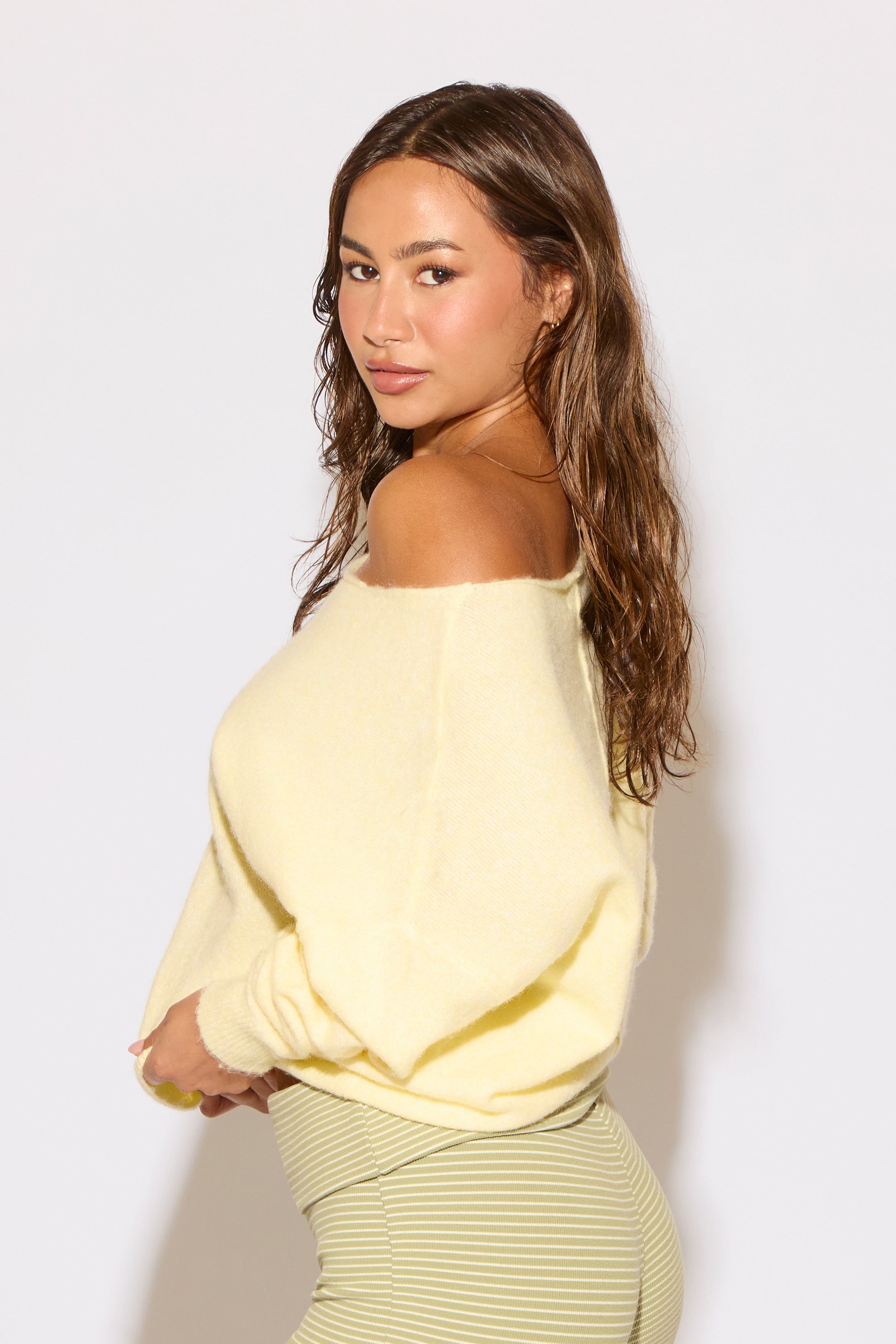 Woman wearing a light yellow off-shoulder top against a white background