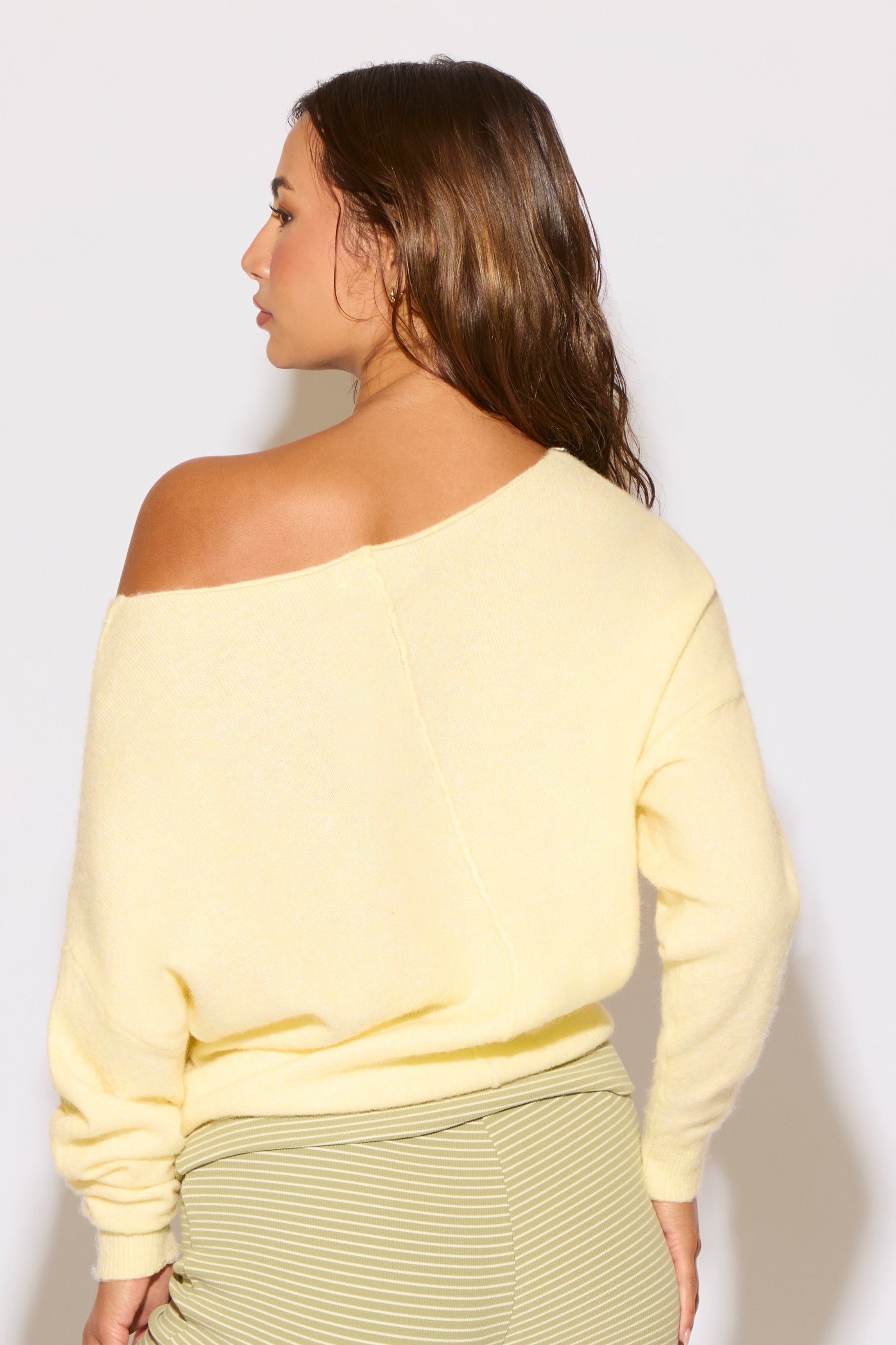 Woman wearing a yellow off-shoulder top against a white background