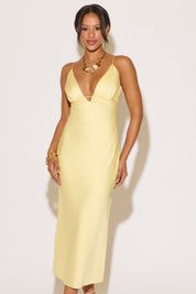 Woman wearing a light yellow slip dress against a white background