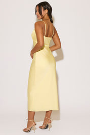 Woman wearing a yellow dress with thin straps against a white background