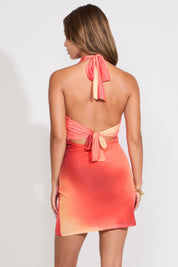 Woman wearing an orange abstract print dress on a white background