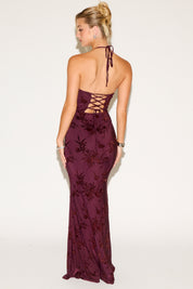 Woman wearing a burgundy floral dress with a lace-up back on a white background