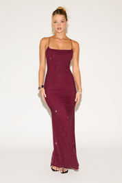 Woman wearing a burgundy dress with sequin details on a white background