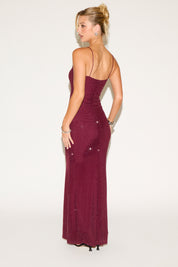 Woman wearing a burgundy evening gown with a white background
