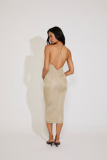 Woman wearing a beige dress with a backless design on a white background