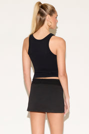 Model wearing a black tank top with a black skirt.