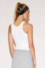 Model wearing a white tank top with a grey skirt .